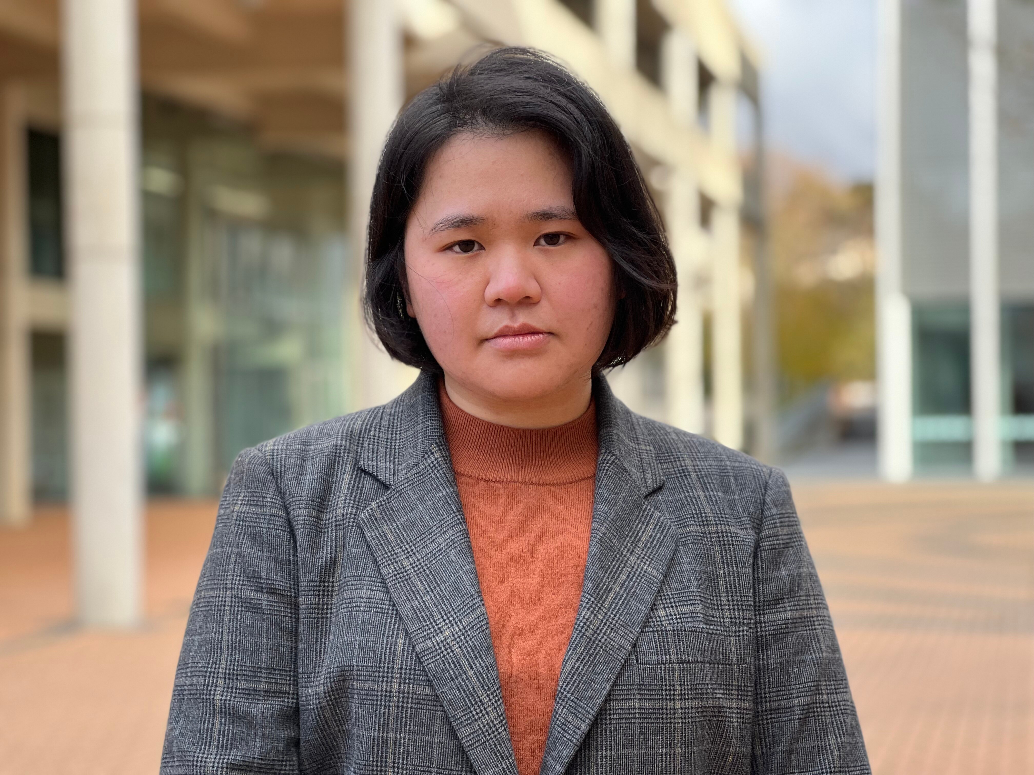 A woman stands on a university campus.