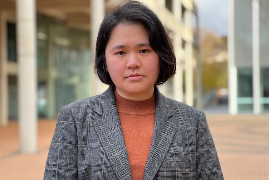 A woman stands on a university campus.