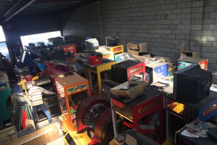 Erwin Boot's warehouse with several arcade games and jukeboxes inside.