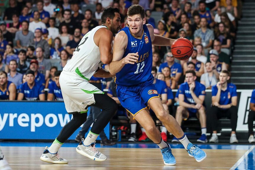 Will Magnay of the Brisbane Bullets drives to the basket on the basketball court.