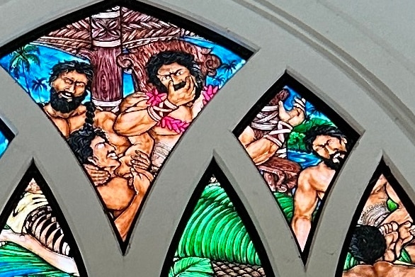 Detail from a stained glass window showing a man wrapped in leaves in the story of King Malietoa.