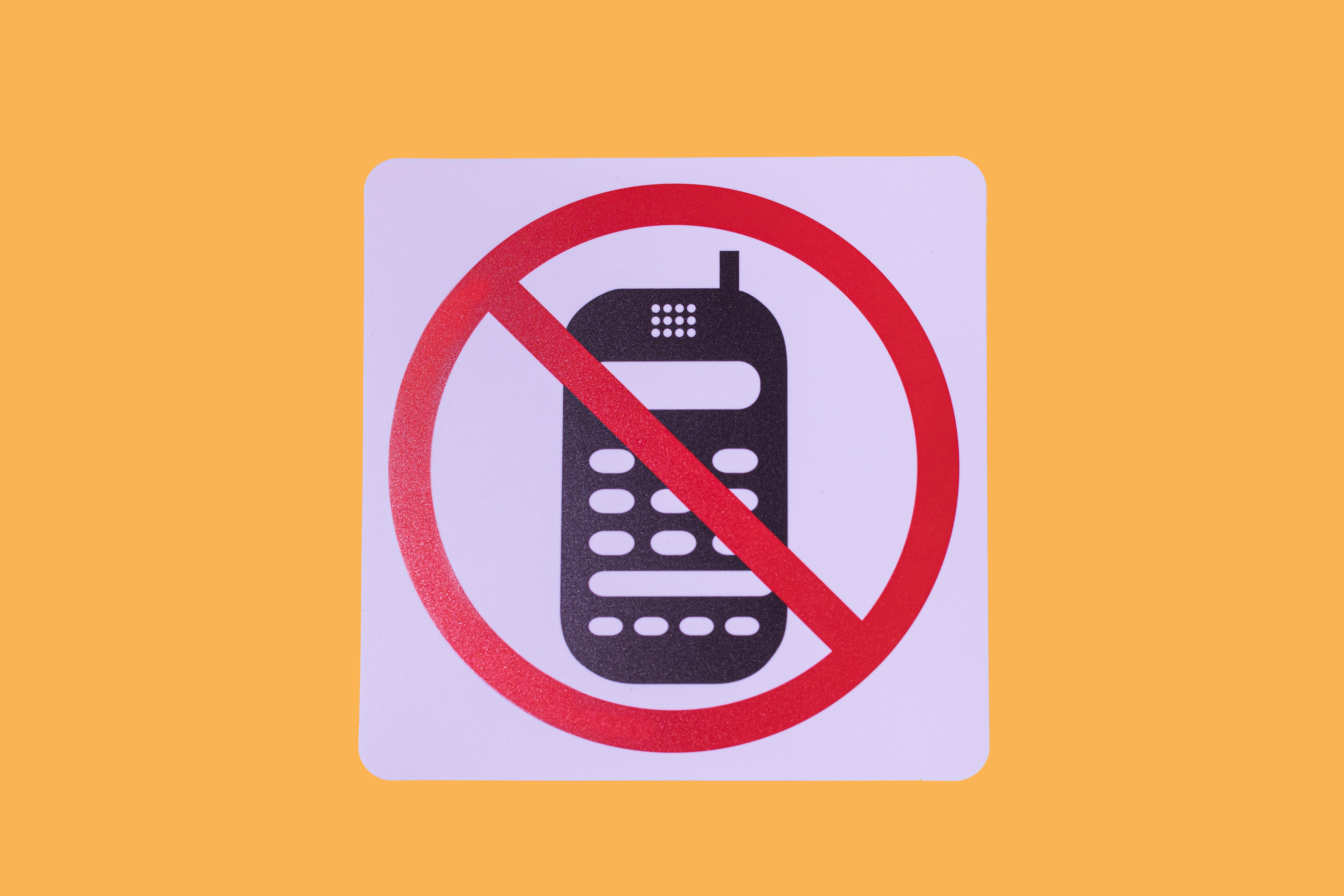 Sign displaying mobile phone with a big red cross through it.