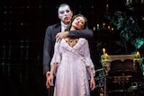 Claire Lyon stands on stage in Phantom of the Opera with the Phantom behind her.