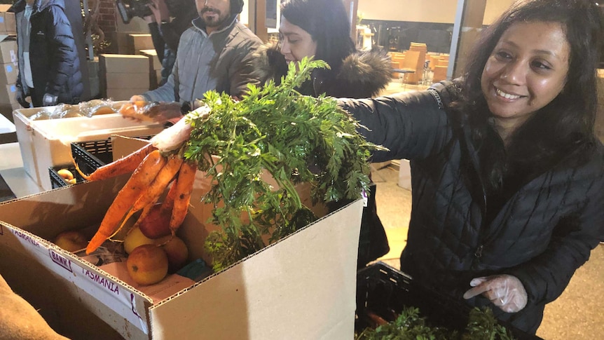 Woman with box of vegetables.