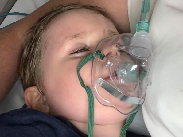 A little boy wearing an oxygen mask in hospital.