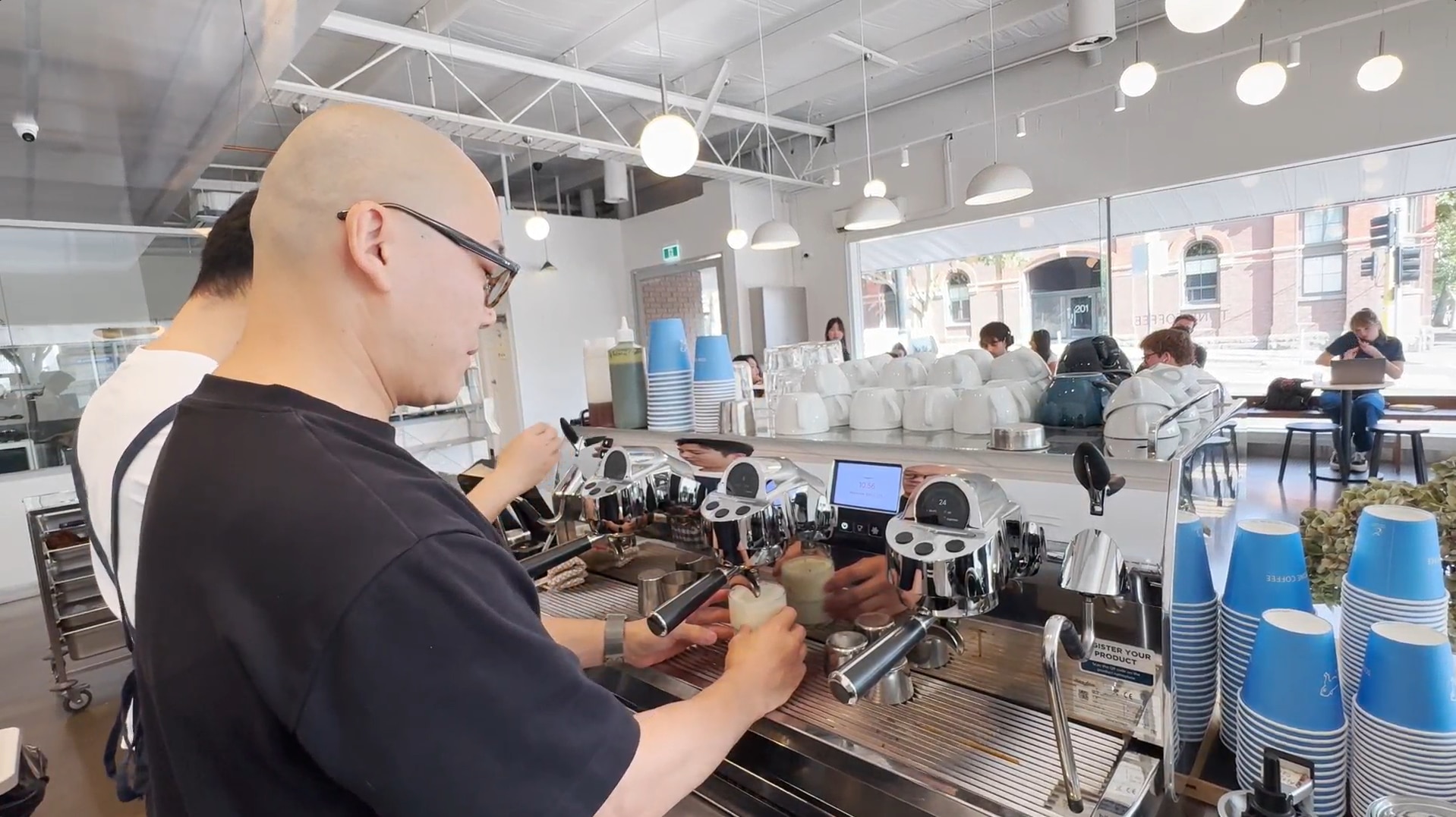 Un hombre detrás preparando café en la máquina.