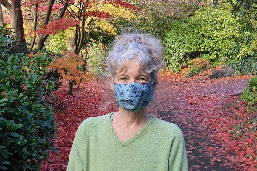 Journalist standing with mask on in park with autumn colours