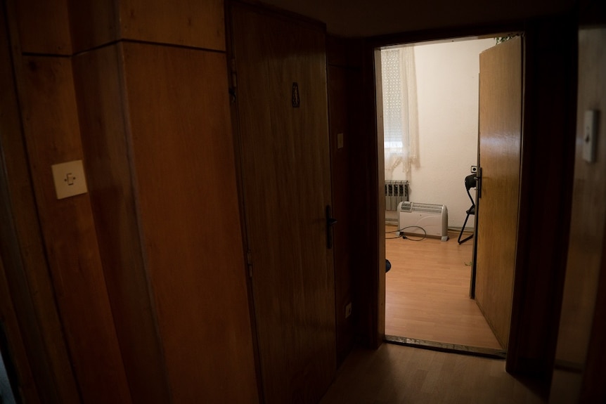 A heater and a chair can be seen through the open door of room