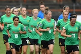 The entire Matildas squad, in training kit, jog around the oval.