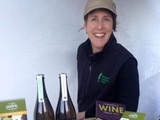 Caro brown stands in front of her bottles of cider at a market stall.