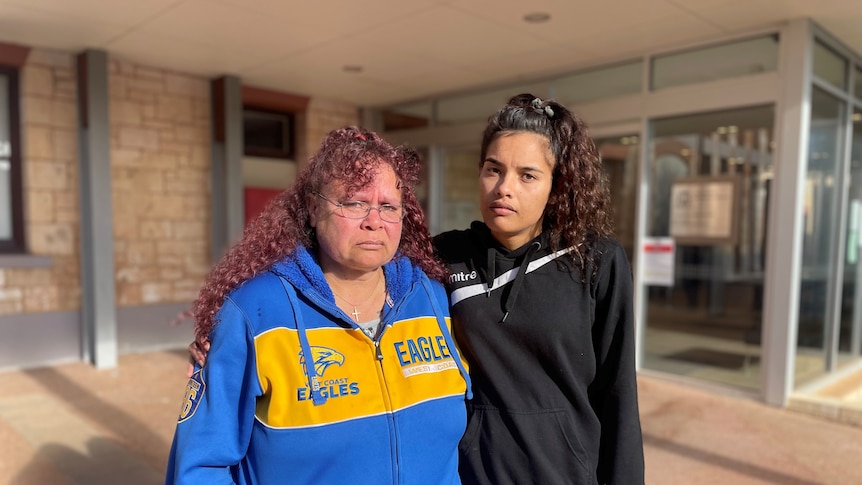 Two women stand in front of the Kalgoorlie Courthouse. They both appear upset. 