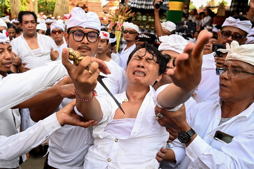 A man is about to jab himself in a Balinese ritual.