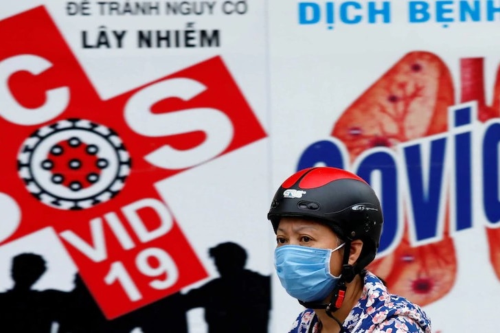 a woman wearing a face mask in front of colourful signs