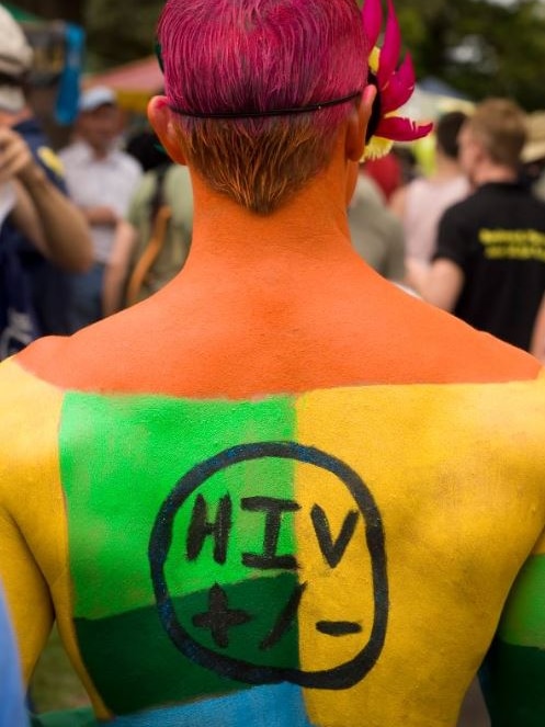 A man painted with the words HIV =/- on his back