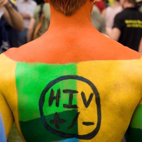 A man painted with the words HIV =/- on his back