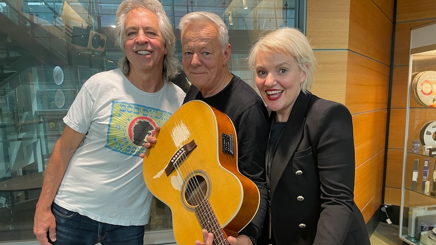 Tommy Emmanuel stands with the Friday Revue's Brian Nankervis and Jacinta Parsons in the ABC Melbourne studios.