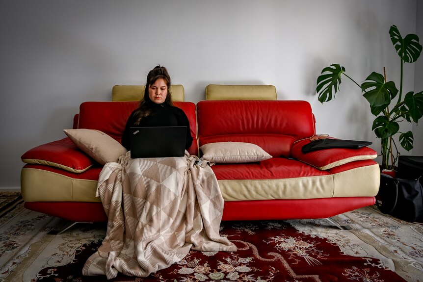 A woman sitting on the couch, using her laptop.