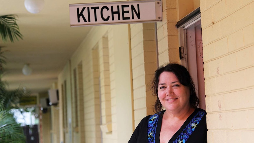 A woman leaning against the brick wall of a backpacker hostel.