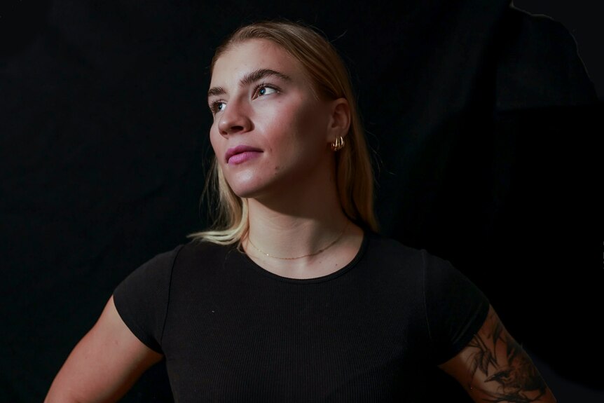 Boxer Marissa Williamson-Pohlman, black shirt, black background, looking to the right stoically