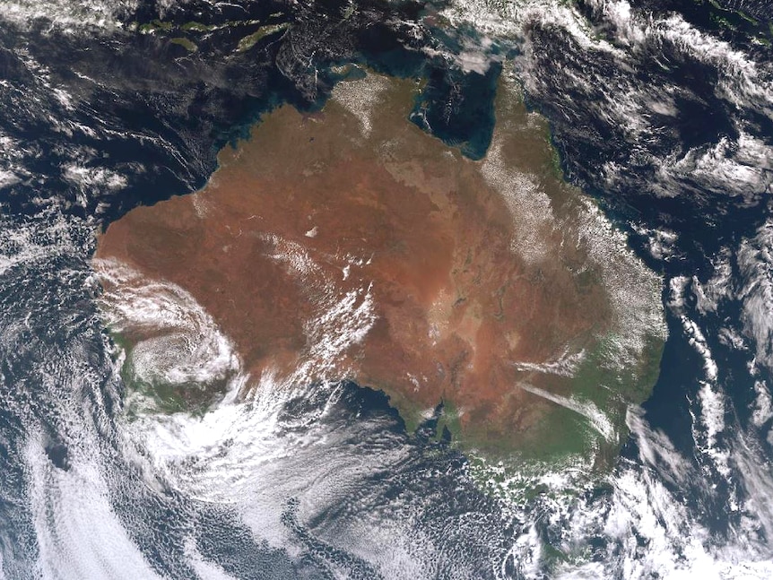 A satellite image of Australia showing building clouds around its coastlines.