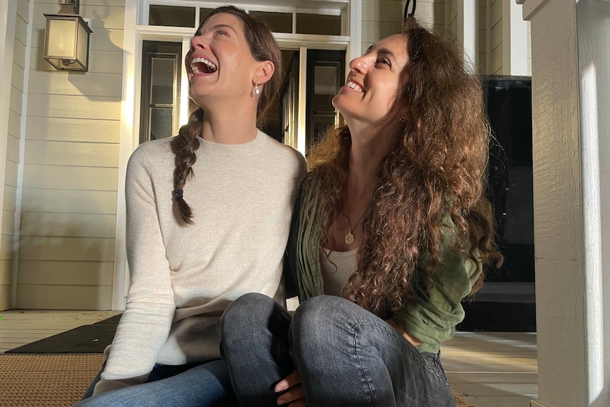 Two women smiling and staring above them. 