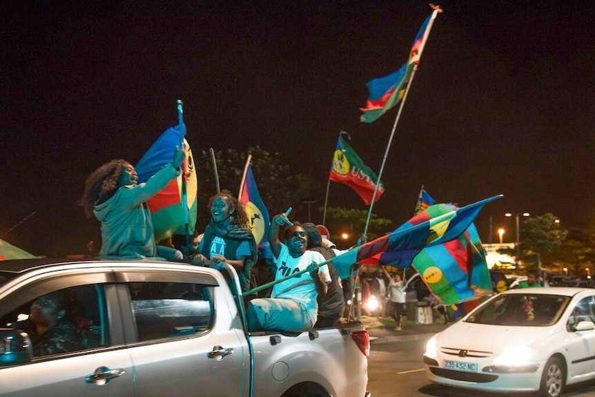 Pro-independence supporters wave flags from the tray of a truck, in Noumea.