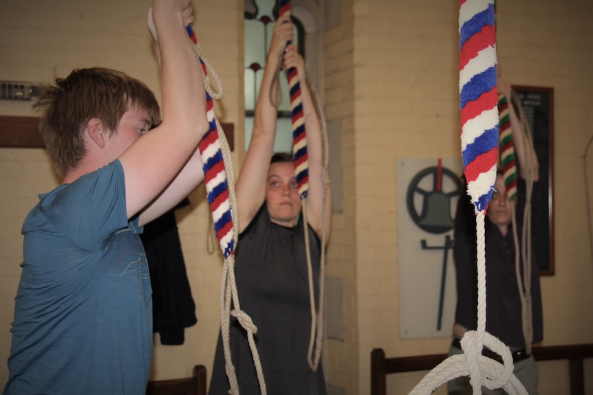 Young people pulling on ropes to ring the church bells.