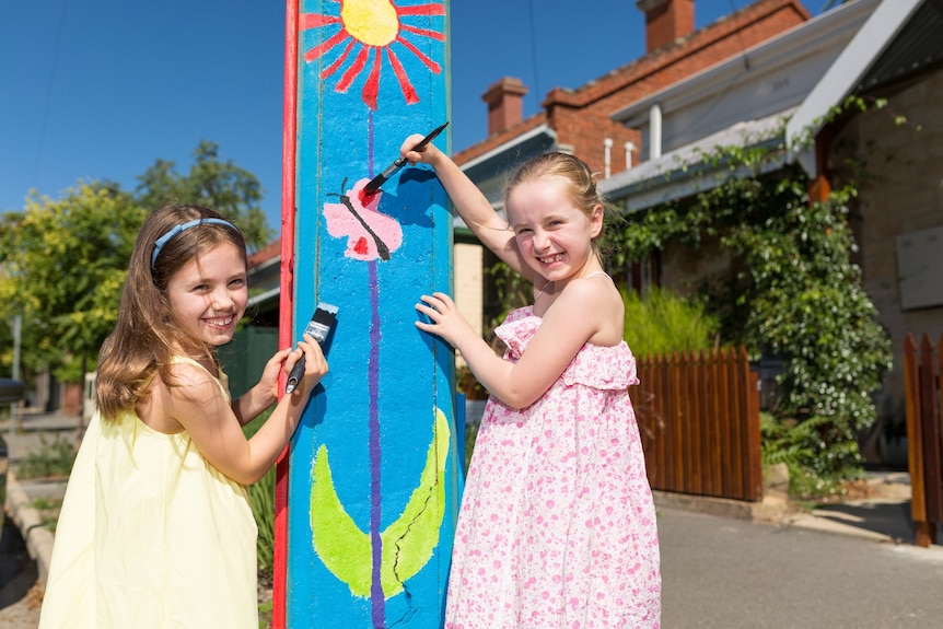 Two young girls paint a Stobie pole
