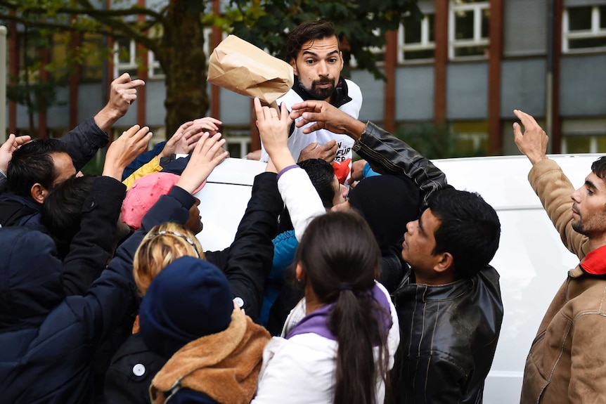 A volunteer hands over care bags to refugees