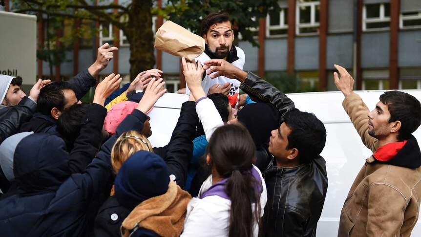 A volunteer hands over care bags to refugees