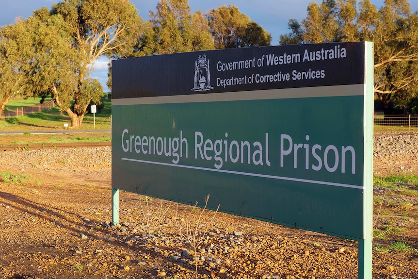 A large sign reading Greenough Regional Prison stands near a road in front of trees.