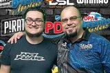 Australian father-son darts duo Ky and Ray Smith smiling for a photo with their arms around one another