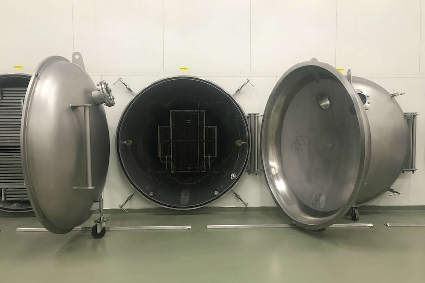 Freeze drying machines with trays in circular cylinders and big doors on them.