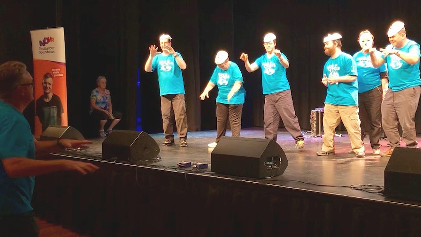 Six adults on stage performing sign language