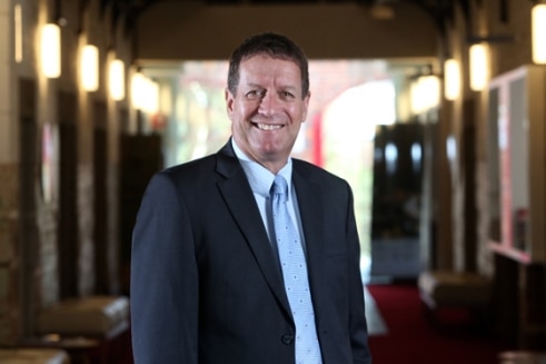 Dale Pearce smiles, wearing a suit.