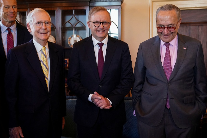 The three men stand side by side and smile.