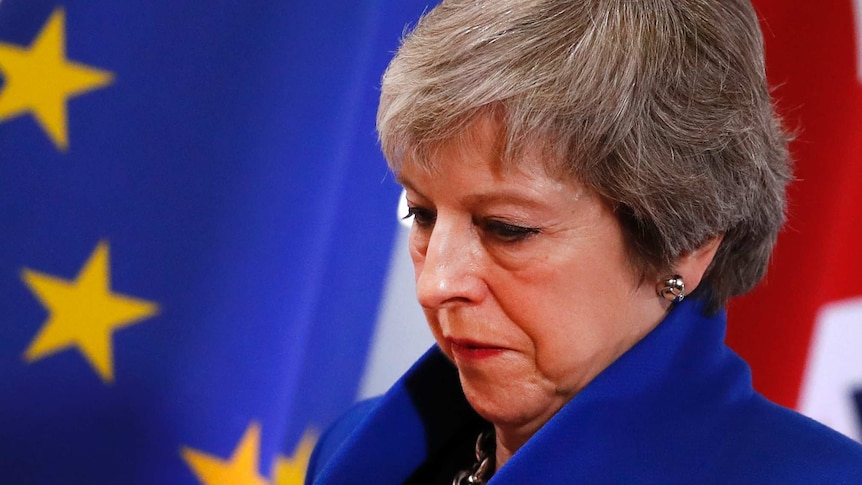 A downcast looking Theresa May with an EU flag in the background