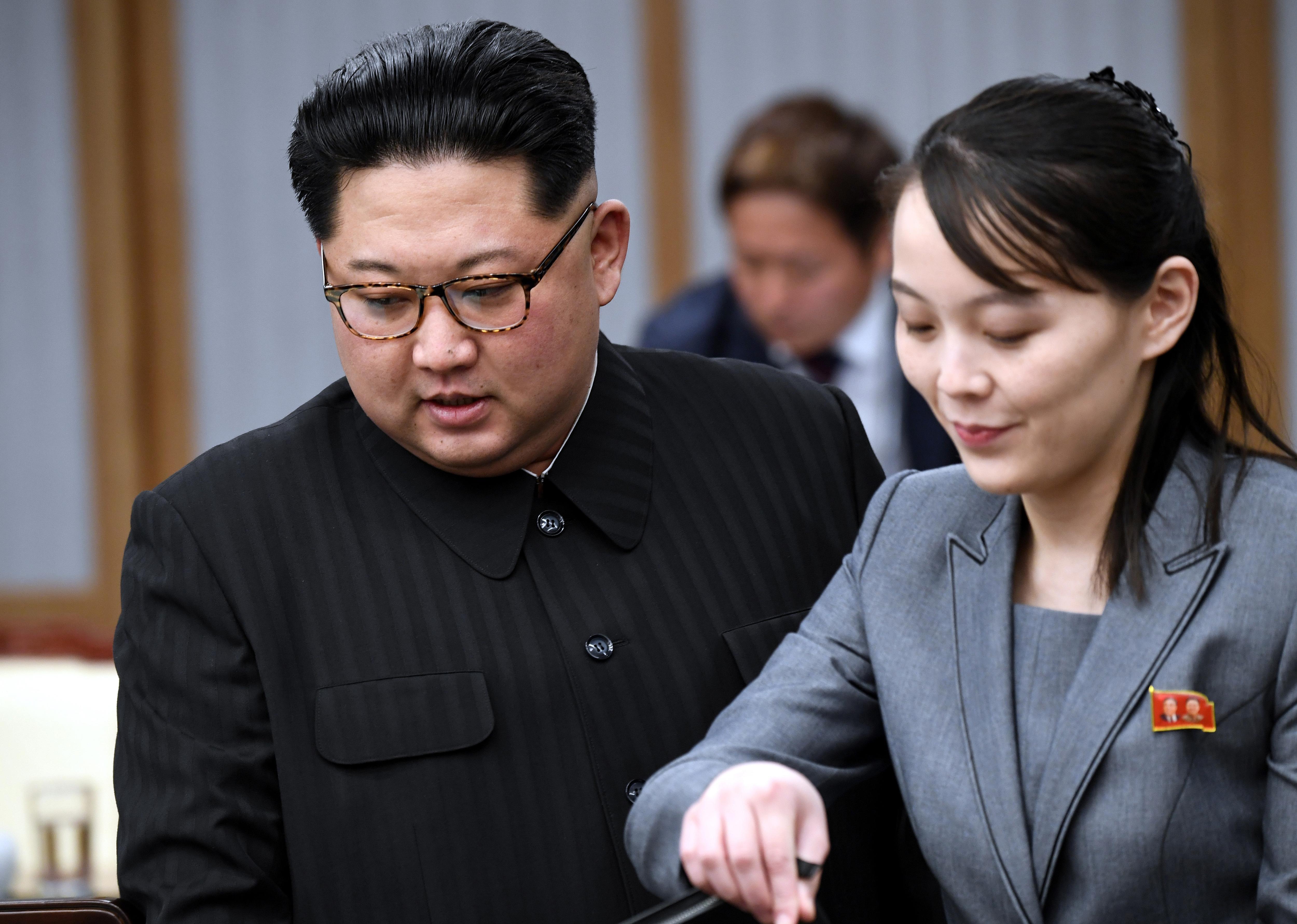 A North Korean man in glasses and a black suit with a North Korean woman in a grey suit