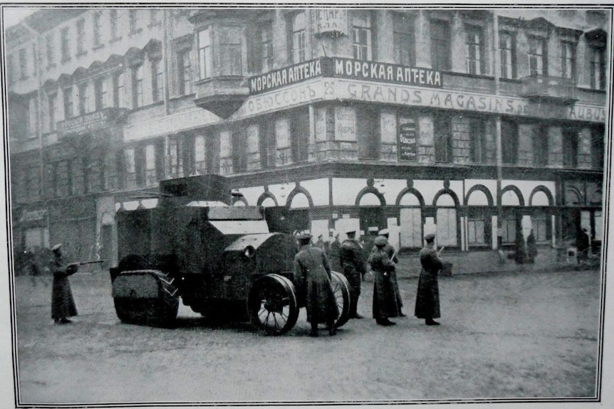 A black and white photo shows uniformed men next to an armoured vehicle