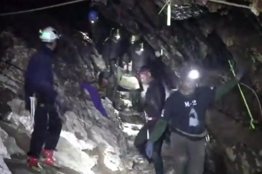 Rescue workers carry a stretcher over rapid flowing floodwater in Tham Luang Cave in Thailand.