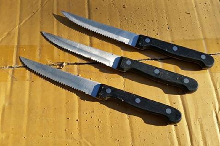 Three steak knives on a piece of cardboard