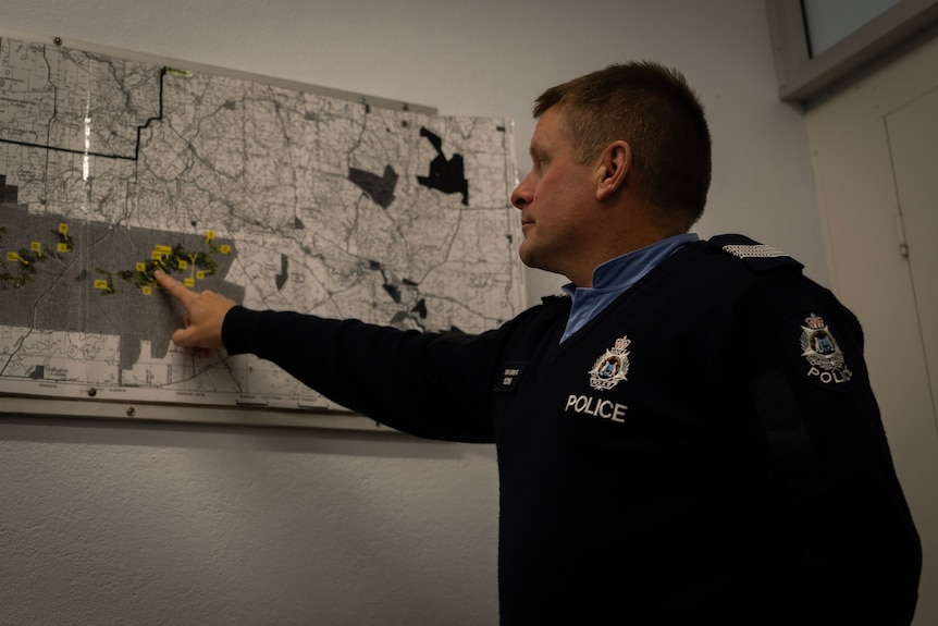 A male police officer points at a map