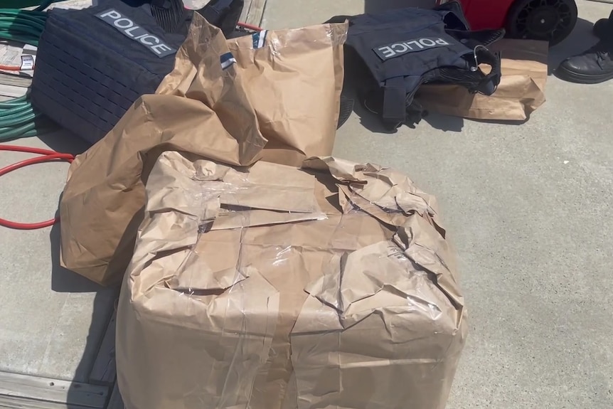 Brown paper bags filled with drugs pictured next to bullet proof police vests