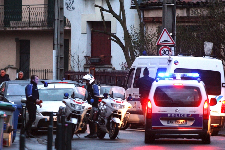 Police stand guard in a Toulouse street after a raid on a house.