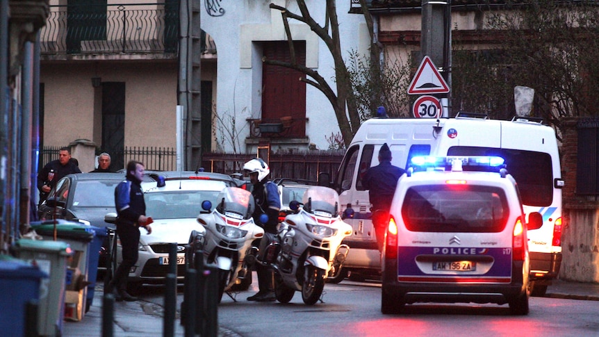 Police stand guard in a Toulouse street after a raid on a house.