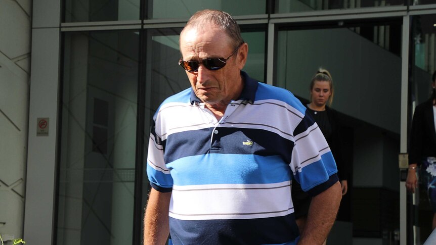 A man wearing a blue and white polo walks down the steps at the Perth court building.