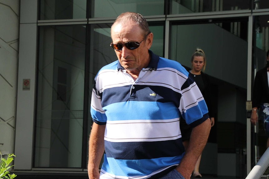 A man wearing a blue and white polo walks down the steps at the Perth court building.