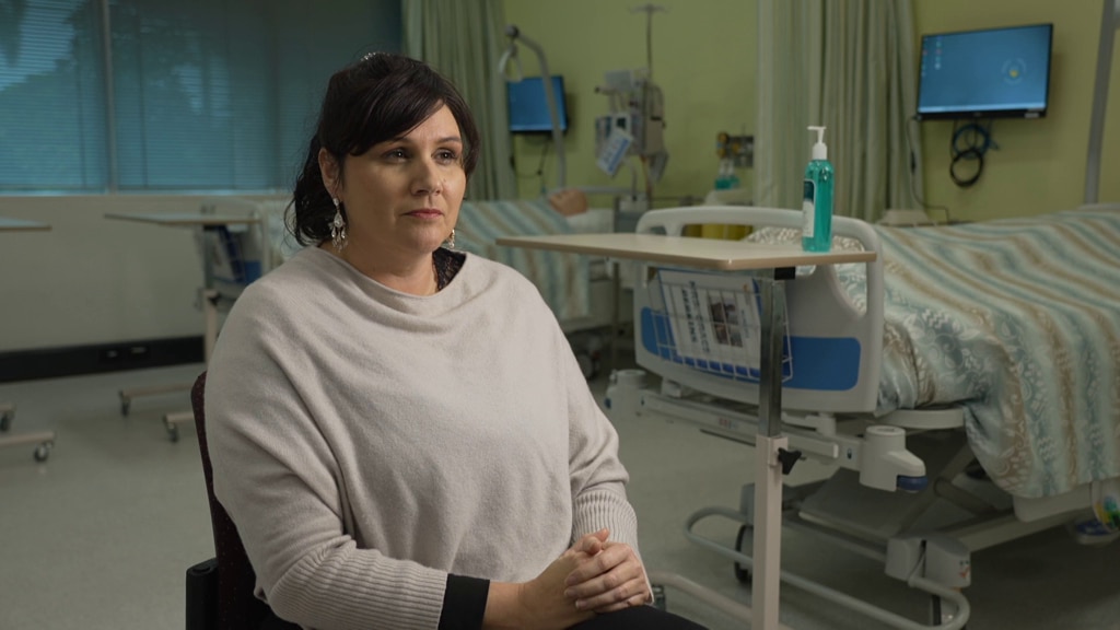Dr Ward sits in a hospital ward looking stern.
