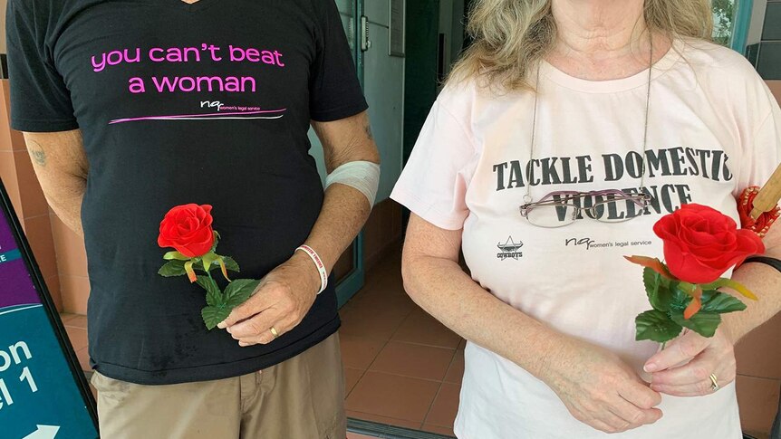 Two people wearing anti-domestic violence t-shirts at a silent Red Rose anti-domestic violence rally in Townsville