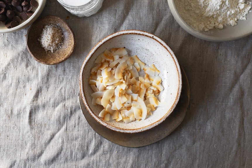 A bowl of toasted coconut for a lamington cake recipe with jam, cream and chocolate ganache.